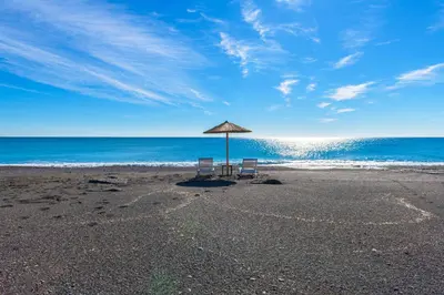 two chairs and an umbrella on a beach at Gennadi Serenity House- beachfront villa with pool in Gennadi