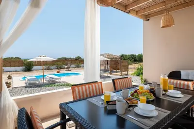a dining room with a table and a view of a pool at Gennadi Serenity House- beachfront villa with pool in Gennadi