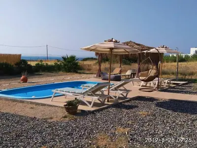 a pool with an umbrella and chairs and a swing at Gennadi Serenity House- beachfront villa with pool in Gennadi