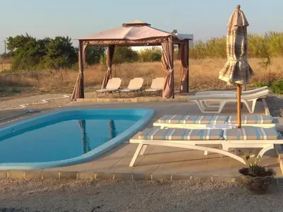 a pool with a gazebo and chairs and an umbrella at Gennadi Serenity House- beachfront villa with pool in Gennadi