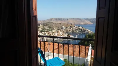 a view from a balcony with a blue chair at Hotel Fiona Symi in Symi