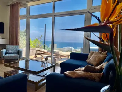 a living room with blue couches and a large window at FlyViewFlatsGOLD PrivateHotTub with SeaView in Rhodes Town