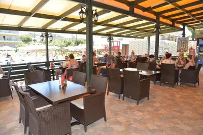 a group of people sitting at tables in a restaurant at Emerald Hotel in Kremasti