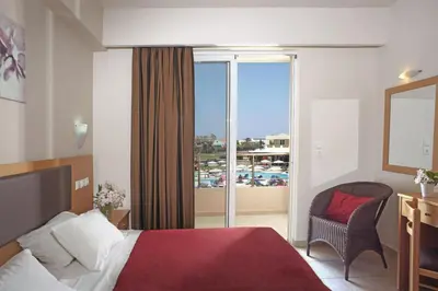 a hotel room with a bed and a chair and a window at Emerald Hotel in Kremasti