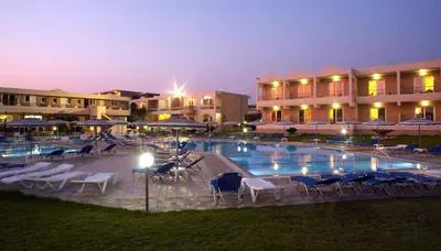 a pool with chairs and umbrellas in front of a hotel at Emerald Hotel in Kremasti