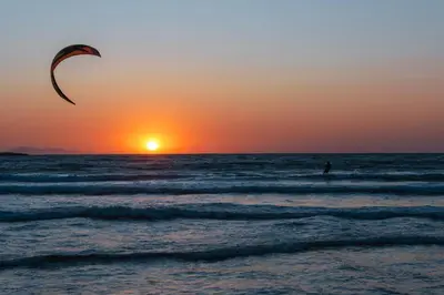 a person flying a kite on the beach at sunset at GOJI Vegan Hotel in Ialyssos