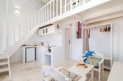 a kitchen and living room with white furniture and a staircase at Atlantis Houses in Halki