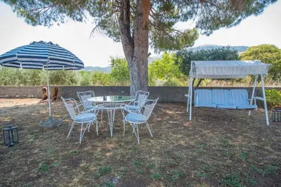 a table and chairs under a tree with an umbrella at Country House in Pastida
