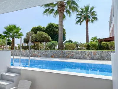 a swimming pool with palm trees in the background at Lardos Bay Hotel in Lardos