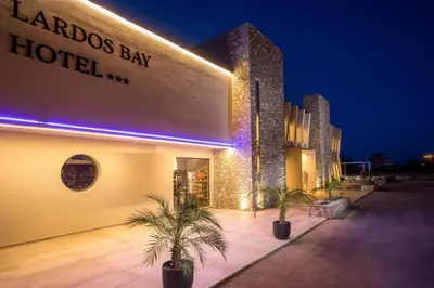 a hotel with palm trees in front of it at night at Lardos Bay Hotel in Lardos