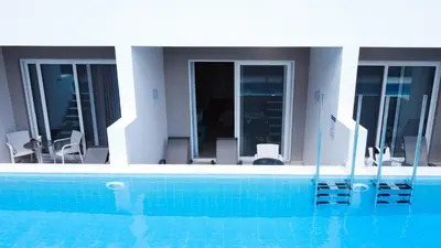 a swimming pool with chairs and a house at Lardos Bay Hotel in Lardos