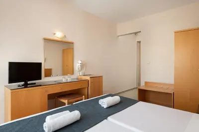 a bedroom with a bed and a desk with a television at Nafsika Hotel in Rhodes Town