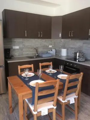 a kitchen with a table and chairs with wine glasses at Melita Apartment Seaside in Haraki