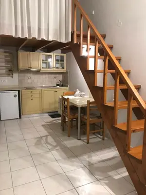 a kitchen and dining room with a wooden staircase at Vlycha Beach Apartments in Líndos