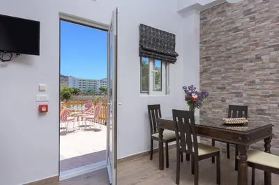 a dining room with a table and chairs and a window at Vlycha Beach Apartments in Líndos