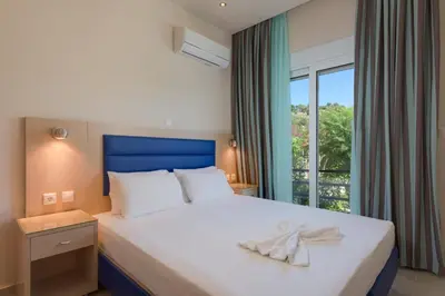 a bedroom with a large white bed with a window at Vlycha Beach Apartments in Líndos