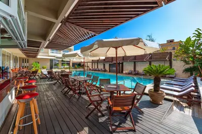 an outdoor patio with tables and chairs and a pool at Athineon Hotel in Rhodes Town