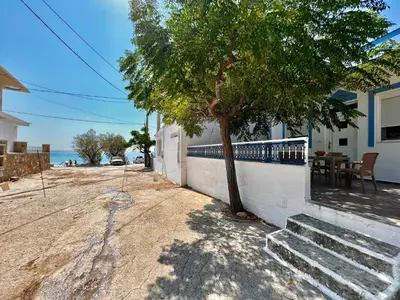 a tree sitting next to a white wall with a table at Stella Beach House in Archangelos
