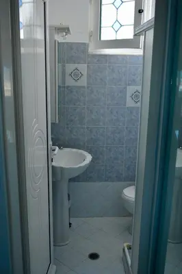 a bathroom with a sink and a toilet and a window at Stella Beach House in Archangelos