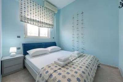 a blue bedroom with a bed and a window at Stella Beach House in Archangelos