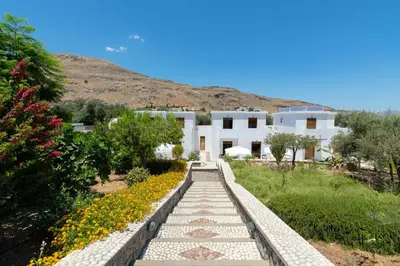 a pathway leading to a white building with flowers at George's Villas in Líndos