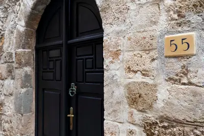 a black door and a stone wall with a sign on it at Belvedere Medieval Villa in Rhodes Town