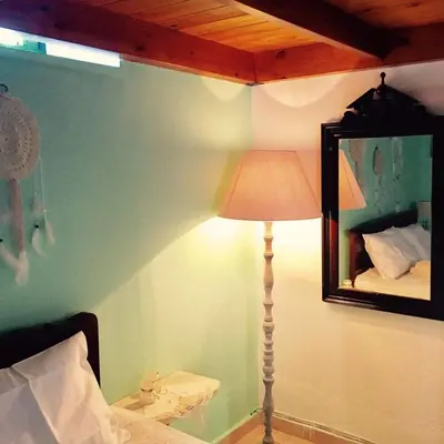 a lamp in a bedroom with a mirror and a bed at Mariza's traditional house 1900 in Soroni