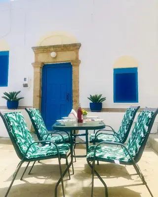 a group of chairs and a table with a blue door at Mariza's traditional house 1900 in Soroni