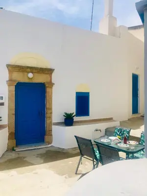 a blue door on a white wall with a table and chairs at Mariza's traditional house 1900 in Soroni