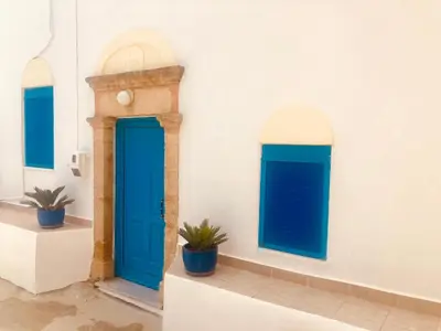 a white wall with blue doors and potted plants at Mariza's traditional house 1900 in Soroni