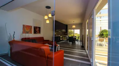 a living room with a red couch and a dining room at Villa Elpiniki in Ixia
