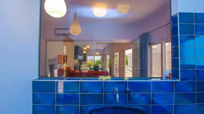 a blue tiled bathroom with a mirror above a sink at Villa Elpiniki in Ixia