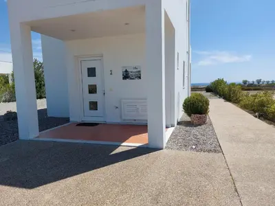 a white building with a white door and a sidewalk at Villa Mangano in Afantou