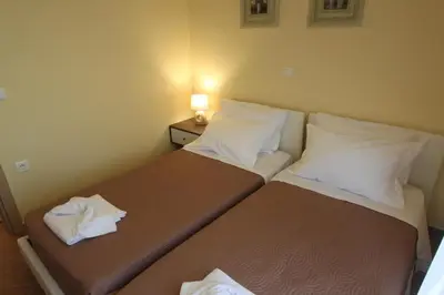two beds in a small room with a lamp on a table at Villa Mangano in Afantou