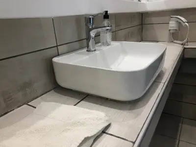 a white sink in a bathroom with a counter at Sotiris rooms in Faliraki