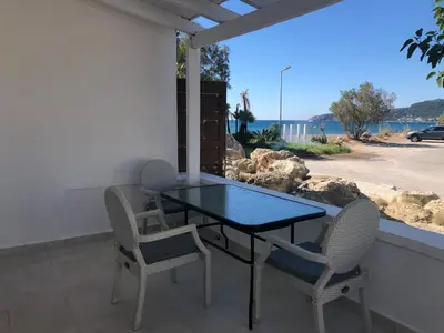 a table and chairs on a balcony with a view of the ocean at Sotiris rooms in Faliraki