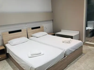 a bedroom with two beds with white sheets at Sotiris rooms in Faliraki