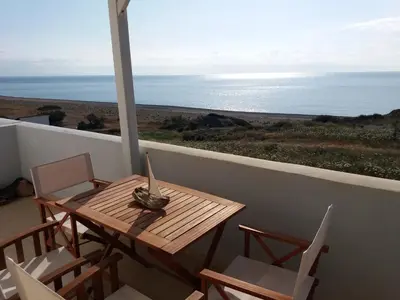 a wooden table and chairs on a balcony with the ocean at Sea House Lahania in Lachania