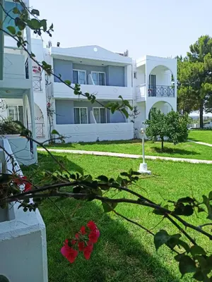 a large white building with red flowers in the yard at Summer Dream in Theologos