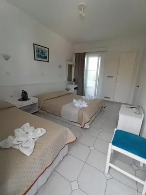 a hotel room with two beds and a blue chair at Summer Dream in Theologos