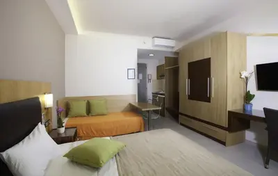 a bedroom with a bed and a desk and a kitchen at Pefkos Beach Studios & Apartments in Pefki Rhodes