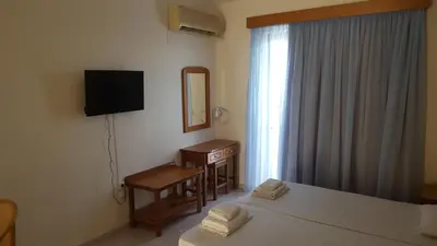 a hotel room with a bed and a desk and a mirror at Panorama Studios in Faliraki
