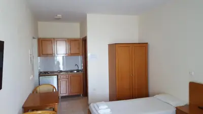 a small kitchen with a bed and wooden cabinets at Panorama Studios in Faliraki
