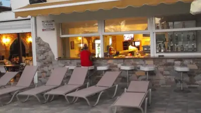a woman standing in front of a bar with chairs at Panorama Studios in Faliraki