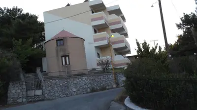a building on a stone wall next to a street at Panorama Studios in Faliraki