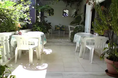 a patio with white tables and chairs and plants at Rosmari Hotel in Archangelos