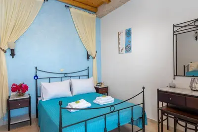 a blue bedroom with a bed and a mirror at Agnanti Beach Apartments in Archangelos