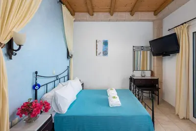 a bedroom with a bed and a television in it at Agnanti Beach Apartments in Archangelos