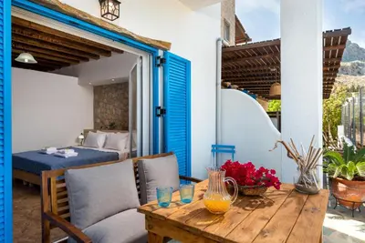 a patio with a table and chairs and a bed at Agnanti Beach Apartments in Archangelos
