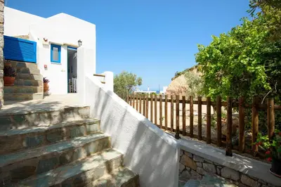 a white house with a fence and stairs at Agnanti Beach Apartments in Archangelos